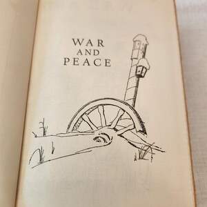 Peut inclure: Une page de livre ouverte pr&eacute;sentant le titre War and Peace en texte noir. Sous le titre se trouve un dessin au trait en noir et blanc d'une roue de chariot en bois partiellement enfouie dans la neige pr&egrave;s d'un r&eacute;verb&egrave;re enneig&eacute;.