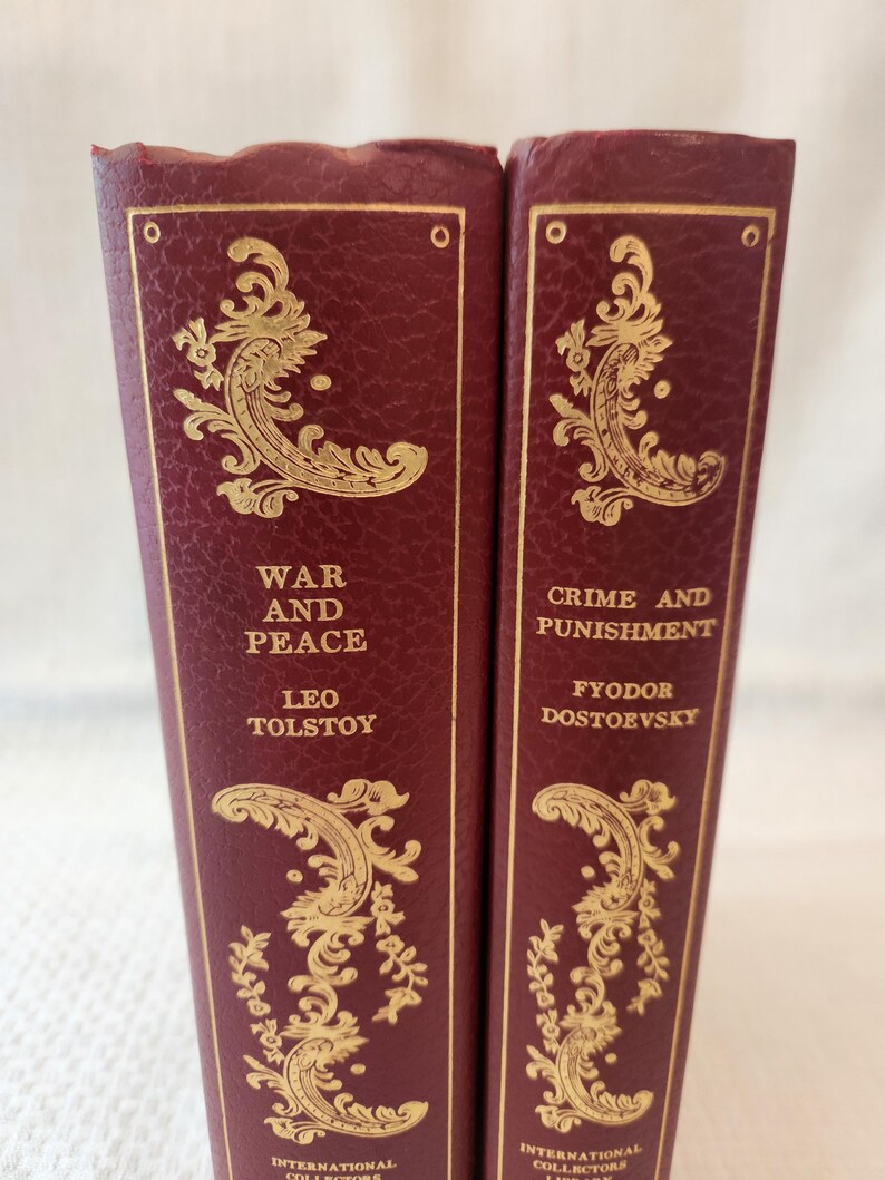 Peut inclure: Deux livres reli&eacute;s bordeaux avec des lettres dor&eacute;es et des motifs en filigrane sur les tranches. Le livre de gauche est intitul&eacute; War and Peace de Leo Tolstoy, et le livre de droite est intitul&eacute; Crime and Punishment de Fyodor Dostoevsky.