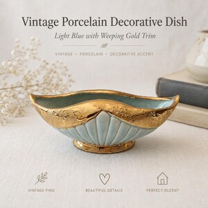 May include: A light blue porcelain decorative dish featuring a scalloped shell-like design and a textured gold metallic trim along the upper rim and base. The dish has an elongated, curved shape with a smooth interior and a glossy finish.