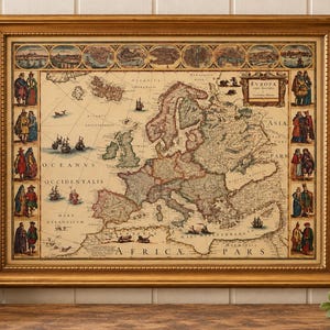 May include: A framed antique-style map of Europe featuring detailed cartography, decorative border illustrations of regional figures, and a top row of city vignettes. The map includes Latin text labels and is enclosed in a gold-toned frame.