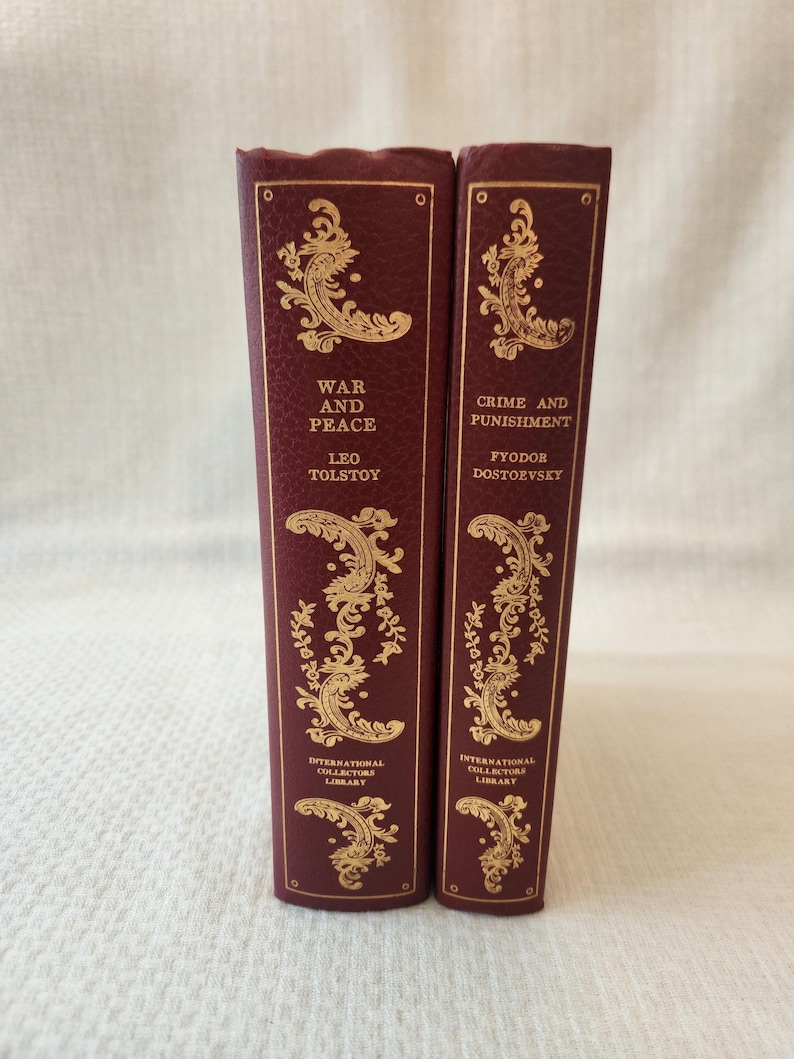 Peut inclure: Deux livres &agrave; couverture rigide bordeaux avec des lettres dor&eacute;es en relief et des motifs d&eacute;coratifs en filigrane sur les tranches. Le livre de gauche est War and Peace de Leo Tolstoy, et celui de droite est Crime and Punishment de Fyodor Dostoevsky.