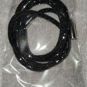 May include: A black multi-strand necklace with silver clasps. The necklace is made of small black beads that have a sparkly finish.