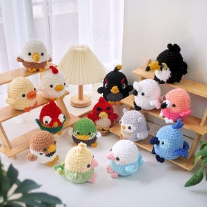 Könnte beinhalten: Eine Sammlung von 15 gehäkelten Stofftieren in verschiedenen Farben und Designs, darunter Vögel, Eulen und andere Kreaturen. Die Tiere sind auf Holzregalen angeordnet.