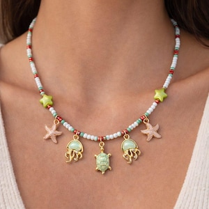 Può includere: Una tazza di ceramica bianca con un manico nero e la scritta "But first, coffee" in stile scritto a mano. La tazza è su una superficie bianca. La tazza è alta 10 cm.