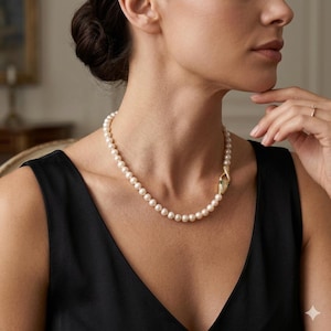May include: A pearl necklace with a gold snake clasp, featuring small green gemstones. The necklace is worn with a black sleeveless top.