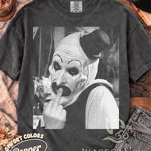 Könnte beinhalten: Ein anthrazitfarbenes Kurzarm-T-Shirt mit einem schwarz-weißen Grafikdruck eines Clowns mit Zylinder, der den Mittelfinger zeigt. Das T-Shirt hat einen Rundhalsausschnitt und eine verwaschene Optik im Vintage-Stil mit Comfort Colors Etikett.