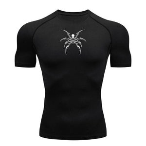 Puede incluir: Camiseta de compresión negra de manga corta con un gráfico de araña blanca en la parte delantera.