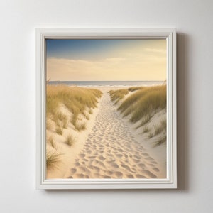 May include: A framed photograph of a sandy path leading to the ocean. The path is lined with tall grass and the ocean is in the distance. The sky is a light blue with some clouds.