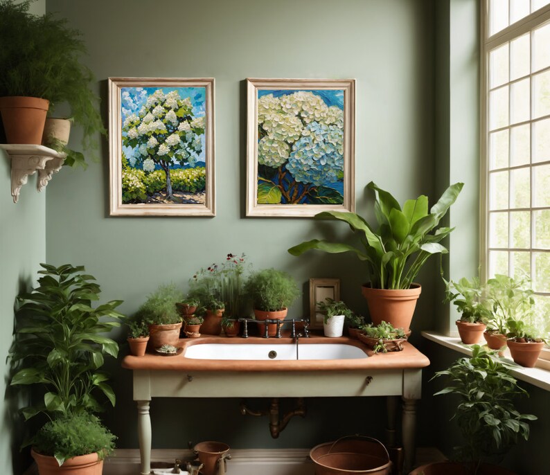 May include: A bathroom with a white porcelain sink and a green wall. There are two framed paintings of white flowers, and several potted plants.