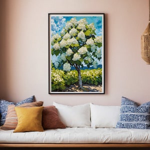 May include: A framed painting of a white flowering tree with green leaves against a blue sky with white clouds. The tree is in a field of green bushes.