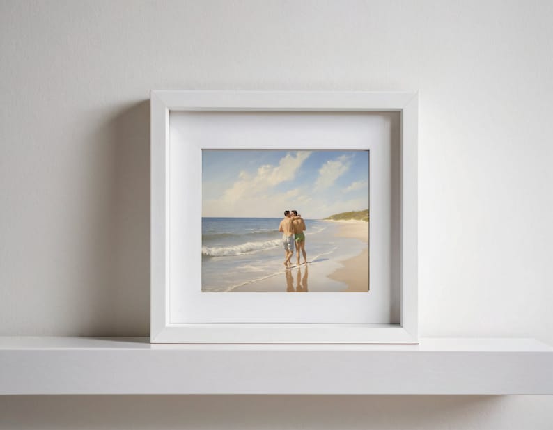 May include: A framed photograph of two people embracing on a beach. The photo is in a white frame and the people are wearing swimsuits.