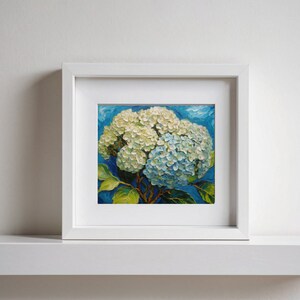 May include: A framed painting of a white and blue hydrangea flower against a blue background.