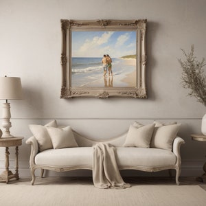 May include: A framed painting of two people walking on a beach. The painting is in a light wood frame with ornate details. The painting is hanging on a white wall above a white couch.