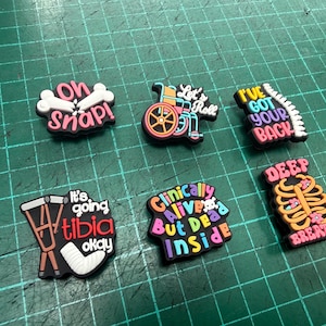 Pu&ograve; includere: Una collezione di ciondoli colorati per scarpe con temi medici e umoristici. I disegni includono frasi come "Oh Snap!", "Let's Roll" e "I've Got Your Back". Altri ciondoli presentano una sedia a rotelle, una gabbia toracica e una gamba rotta.