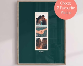 May include: A vertical rectangular wall art print with a dark teal background featuring a central white film strip containing three photographs of a couple. The photos show a couple embracing, hands holding, and a close-up of the couple. The date 22.08.25 is printed below the film strip.