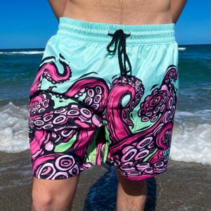 Puede incluir: Bañador azul aguamarina con estampado de pulpo rosa y verde. Los tentáculos del pulpo están envueltos alrededor de las piernas del bañador.