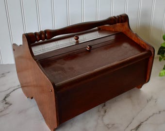 Caja de costura de madera vintage con asa y tapa de doble bisagra, ideal para guardar artículos de manualidades.