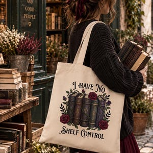 Peut inclure: Un sac fourre-tout en toile couleur crème avec une illustration graphique de trois livres anciens entourés de vignes épineuses et de roses rouges. Le texte "I HAVE NO SHELF CONTROL" est imprimé en noir au-dessus et en dessous.