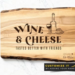 May include: A wooden serving board with the words "WINE & CHEESE" engraved in a dark brown font. The board features a wine bottle, a wine glass, and a cheese wedge illustration. The text "TASTES BETTER WITH FRIENDS" is also engraved.