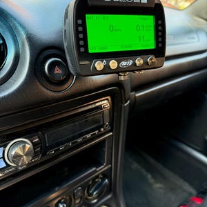 Puede incluir: Un registrador de datos GPS Solo2 DL negro con una pantalla verde que muestra "SAT 11 3", "0 RPM", "GPS GOOD", "520009", "Pagina", "0.1", "11" y el logotipo de AIM.