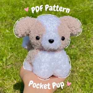 Op de afbeelding: Een wit en bruin pluche hondenspeelgoed met zwarte ogen en een roze neus. Het speelgoed zit in een hand en de tekst "PDF Pattern Pocket Pup" staat onder het speelgoed.