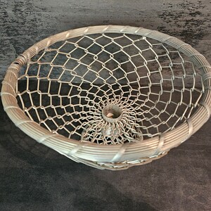 May include: A silver wire mesh basket with a circular base and a woven rim. The basket is made of a fine wire mesh and has a delicate, airy appearance.