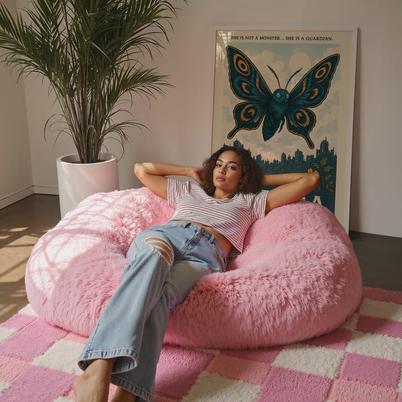 May include: A pink, fluffy beanbag chair with a woman wearing a striped shirt and ripped jeans. A large framed poster with a butterfly illustration hangs on the wall. The rug has a pink and white checkered pattern.