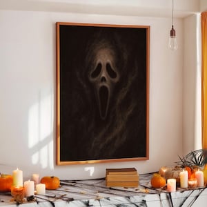 May include: A framed Halloween-themed artwork featuring a ghostly face with an open mouth, set against a dark background. The artwork is in a wooden frame. The scene is decorated with pumpkins, candles, and a spiderweb.