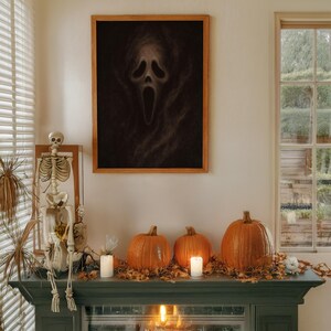 May include: A Halloween-themed display featuring a framed Scream mask print, pumpkins, candles, and a skeleton. The pumpkins are orange, and the candles are white. The framed print is brown and black. The mantel is green.