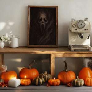 May include: A wooden framed print of the Scream mask hangs above a wooden shelf. The shelf displays a coffee machine, pumpkins, candles, and a white teapot. The pumpkins are orange and green, and the candles are lit.