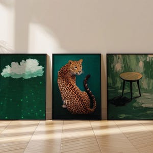Op de afbeelding: Drie ingelijste kunstprints met een groene achtergrond. De linker print toont een witte wolk met groene regendruppels. De middelste print toont een luipaard dat op een turquoise achtergrond zit. De rechter print toont een zwarte kruk met een ronde houten zitting op een groene achtergrond.