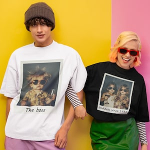 Puede incluir: Dos personas vistiendo camisetas con estampados fotogr&aacute;ficos. La camiseta blanca tiene una foto de un ni&ntilde;o con gafas de sol y el texto "The boss". La camiseta negra tiene una foto de dos personas con gafas de sol y el texto "Baddies since 1985".