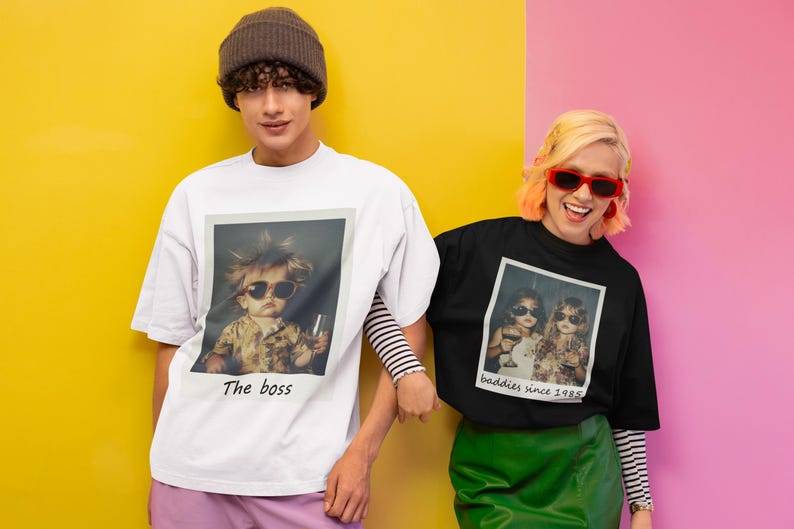 Puede incluir: Dos personas vistiendo camisetas con estampados fotogr&aacute;ficos. La camiseta blanca tiene una foto de un ni&ntilde;o con gafas de sol y el texto "The boss". La camiseta negra tiene una foto de dos personas con gafas de sol y el texto "Baddies since 1985".