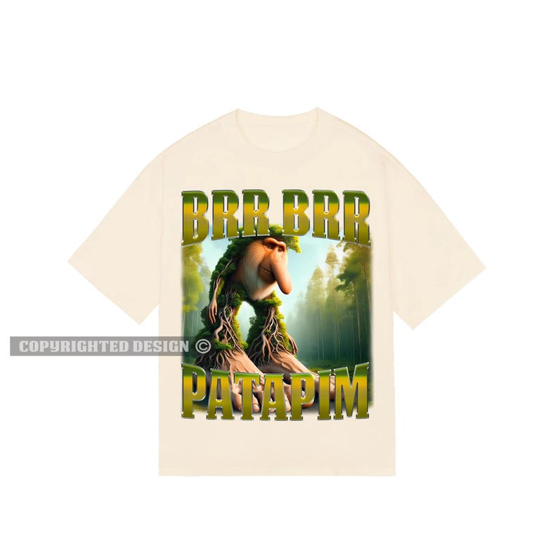 May include: A cream-coloured t-shirt with a green, brown and yellow graphic print of a creature with a long nose and the text "BRR BRR PATAPIM".