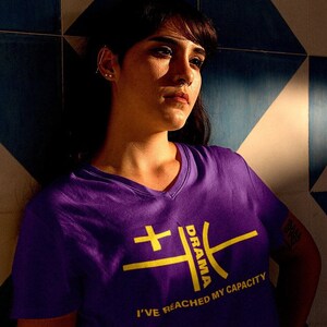 May include: A purple t-shirt with a yellow graphic design that says "Drama" and "I've reached my capacity".