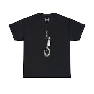 May include: Black t-shirt featuring a detailed image of a metal hook and hardware. The design is centered on the shirt and appears to be a photograph. A small circular logo is visible near the neckline.