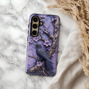 May include: A purple phone case with a 3D design of a tree with flowers and a black raven. The case has a camera cutout with three lenses.