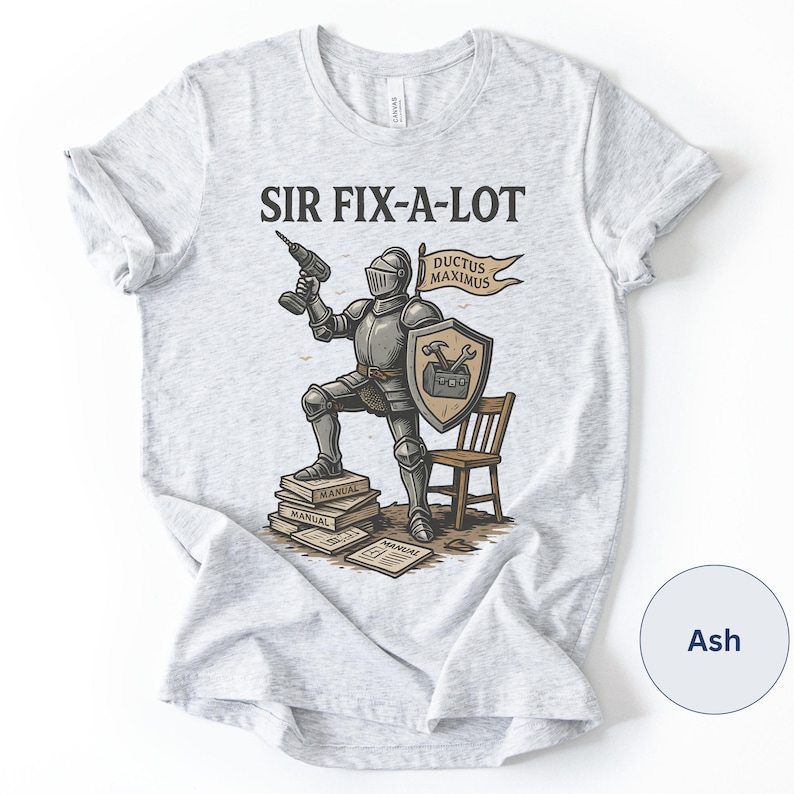 Peut inclure: T-shirt gris clair avec l'inscription "SIR FIX-A-LOT" et un chevalier en armure tenant une perceuse. Le chevalier est debout sur des manuels, avec un bouclier et une banni&egrave;re indiquant "DUCTUS MAXIMUS". Une petite chaise en bois est &agrave; droite.