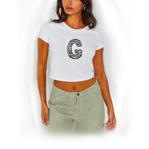 May include: White cropped t-shirt with a black and white zebra print letter "G" on the front.