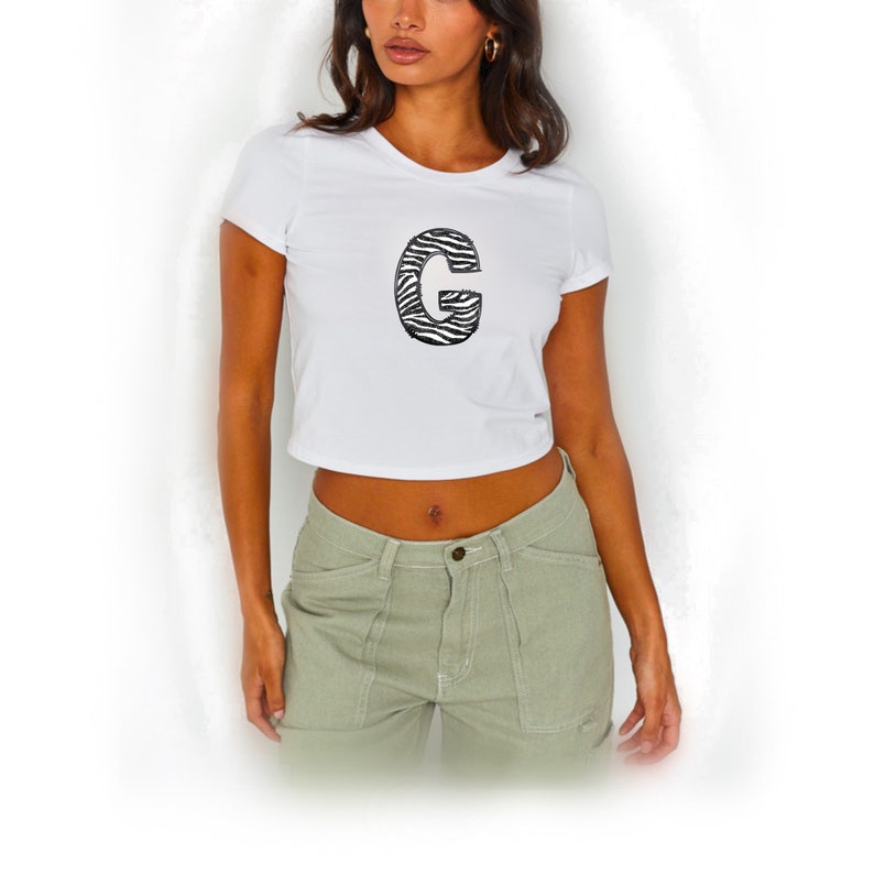May include: White cropped t-shirt with a black and white zebra print letter "G" on the front.