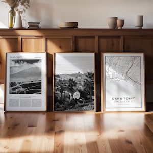 Puede incluir: Tres impresiones enmarcadas en blanco y negro de Dana Point, California. Las impresiones están en un estante de madera con un acabado de madera clara. Las impresiones son todas del mismo tamaño y tienen un marco negro simple.