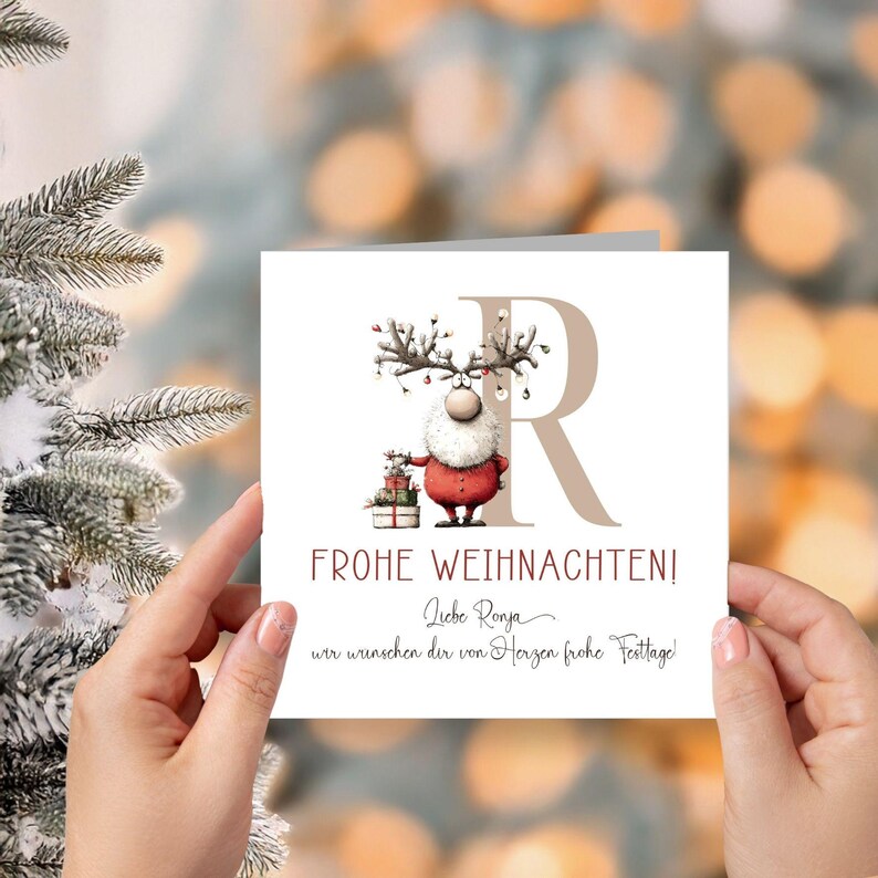 Pu&ograve; includere: Un biglietto di Natale con un Babbo Natale dei cartoni animati con corna di renna, che tiene dei regali. Il biglietto mostra il testo "FROHE WEIHNACHTEN!" e una grande lettera "R". Lo sfondo &egrave; sfocato con luci bokeh.