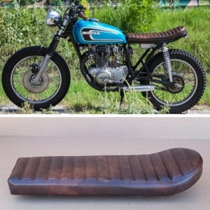 Könnte beinhalten: Ein brauner Ledersitz für ein Motorrad mit geripptem Design. Der Sitz ist für ein Vintage-Motorrad von Honda konzipiert.