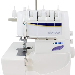 May include: White Juki MO-1000 serger with a clear plastic cover over the needle area. The serger has a white base and a white and blue Juki Easy Thread label.