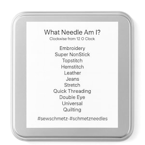 Op de afbeelding: Een zilveren metalen doos met een wit etiket. Het etiket heeft de tekst "What Needle Am I?" en een lijst met naaldtypen, waaronder Embroidery, Jeans en Quilting. De hashtags #sewschmetz en #schmetzneedles staan onderaan.
