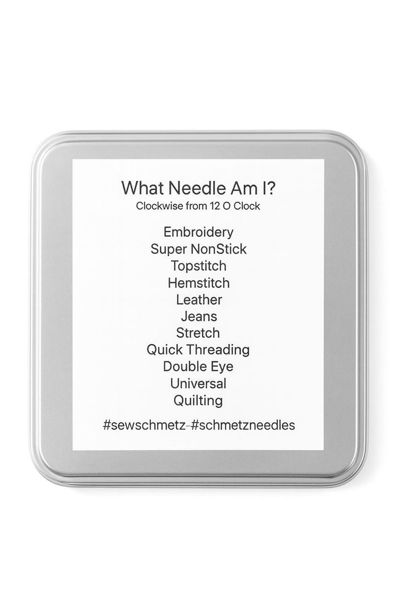 Op de afbeelding: Een zilveren metalen doos met een wit etiket. Het etiket heeft de tekst "What Needle Am I?" en een lijst met naaldtypen, waaronder Embroidery, Jeans en Quilting. De hashtags #sewschmetz en #schmetzneedles staan onderaan.