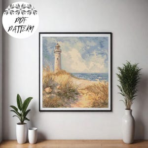 May include: Framed cross-stitch art featuring a coastal scene with a lighthouse on a sandy dune. The artwork depicts a beige lighthouse under a cloudy blue sky, with a path leading to the ocean. The text "PDF PATTERN" is in the upper left corner.