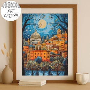 Puede incluir: Arte de punto de cruz enmarcado que representa un paisaje urbano nocturno. La obra de arte presenta un gran edificio con cúpula, otros edificios, árboles y una luna llena en un cielo azul. El marco es de color marrón cálido. El texto "PDF PATTERN" está en un círculo en la esquina superior izquierda.