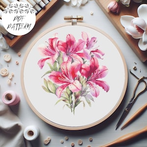 May include: A cross-stitch pattern featuring a bouquet of pink lilies in a wooden embroidery hoop. The pattern is ready to be stitched.