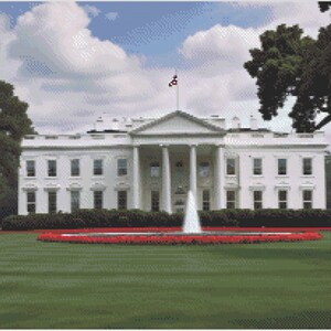 May include: A white building with a fountain in front of it. The building has a large lawn in front of it with red flowers.